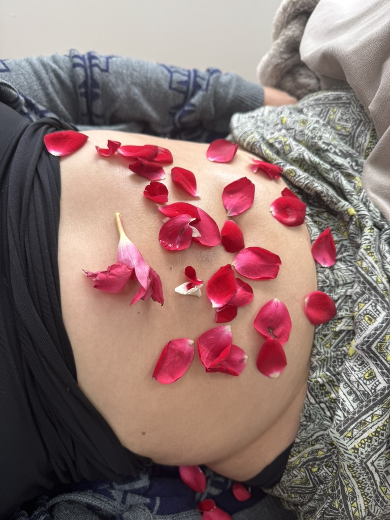 Close-up of deep pink and red rose petals scattered across the womb during ceremony.